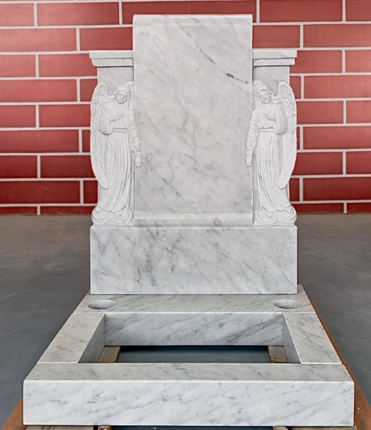 White marble memorial featuring carved angel figures and a substantial kerb surround
